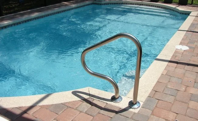 a swimming pool with a metal hand rail.