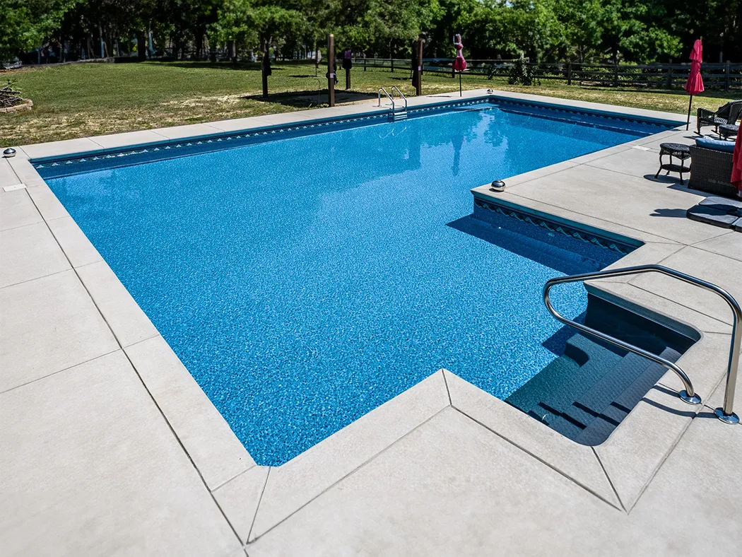 a swimming pool in a backyard with a deck. - Prestige Pools - Prestige Pools a swimming pool in a backyard with a deck.