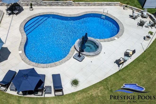 an aerial view of a swimming pool. - Prestige Pools 18x37x29 lagoon shape vinyl liner pool with a spillover spa