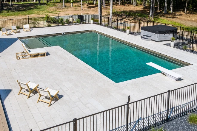 An aerial view of a swimming pool in a backyard. - Prestige Pools A True L shape pool with a tanning ledge and diving board