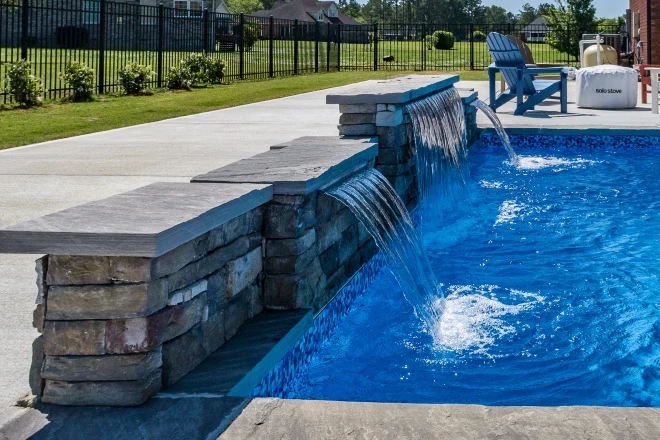 A swimming pool with a waterfall in the middle. - Prestige Pools A True L shape pool with vinyl steps and a waterfall