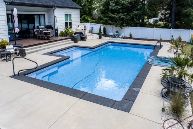 A swimming pool in a backyard with a patio. - Prestige Pools A swimming pool in a backyard with a patio.