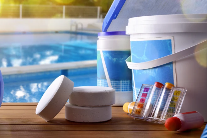 a bucket of pool supplies next to a pool. - Prestige Pools Various pool chemicals and cleaning equipment