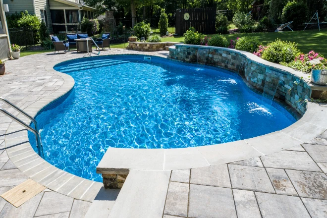 A swimming pool in a backyard with a patio. - Prestige Pools A 20 x 40 rectangle vinyl pool with corner steps and a water fall.