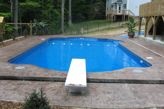 A swimming pool in a backyard with a deck. - Prestige Pools A Roman End style vinyl liner pool installed by Prestige Pools of NC