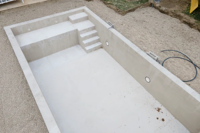 A concrete swimming pool in a backyard. - Prestige Pools A concrete pool shell under construction