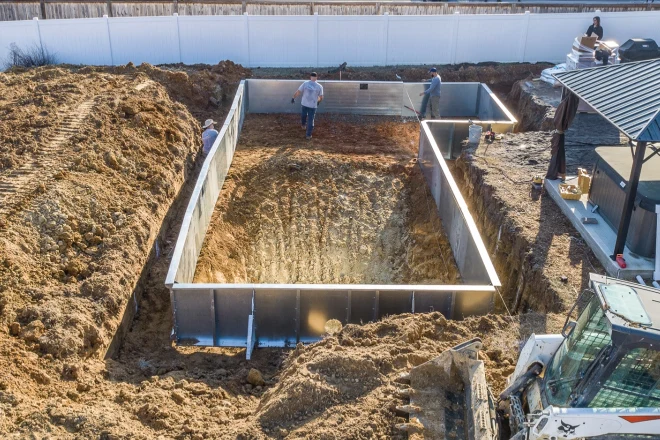 A construction crew is working on a swimming pool. - Prestige Pools A vinyl pool installation during the second day of work. Steel wall panels are visible