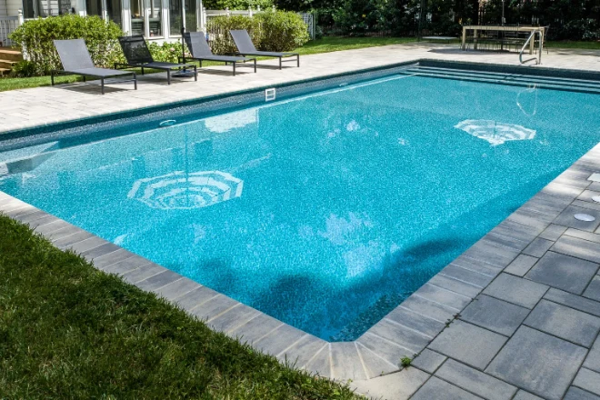 A swimming pool in a backyard with patio furniture. - Prestige Pools A swimming pool in a backyard with patio furniture.