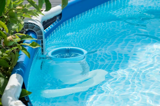 A blue swimming pool with a blue bucket in it. - Prestige Pools An above-ground pool skimmer that is attached to the outer wall